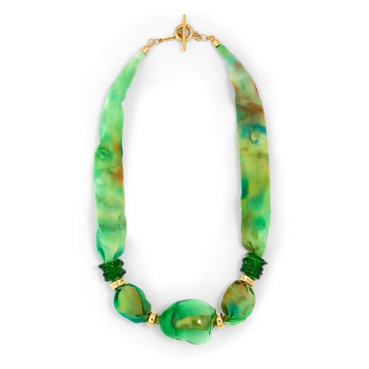 A statement necklace made with green silk and large beads of glass.